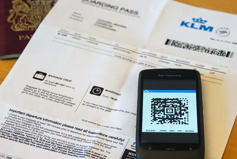 A passport, printed boarding pass, and mobile boarding pass laid out on a desk before a flight
