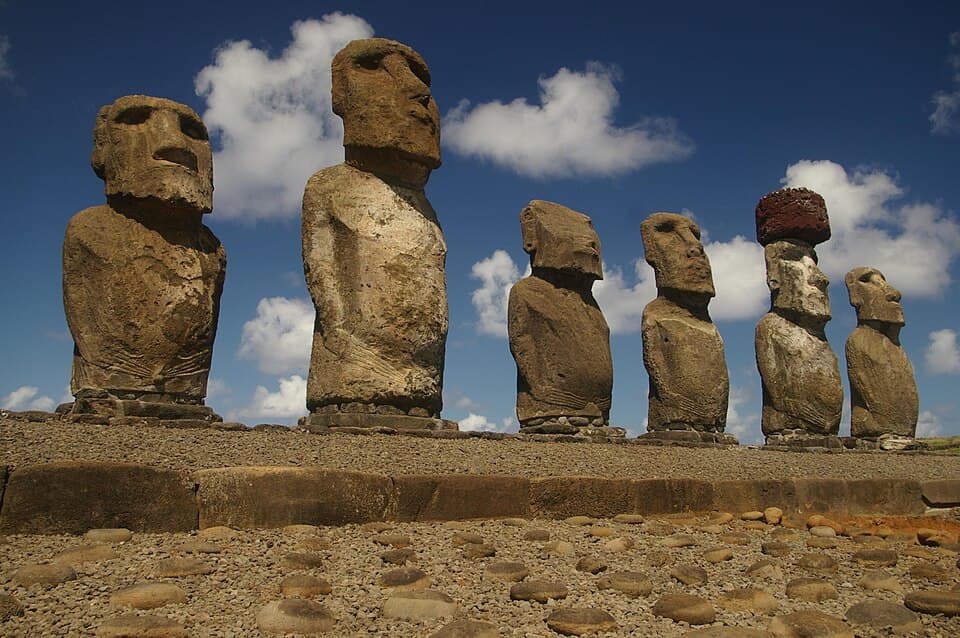 Six moai statues stand in a row atop the stone platform of Ahu Tongariki on Easter Island beneath a blue sky